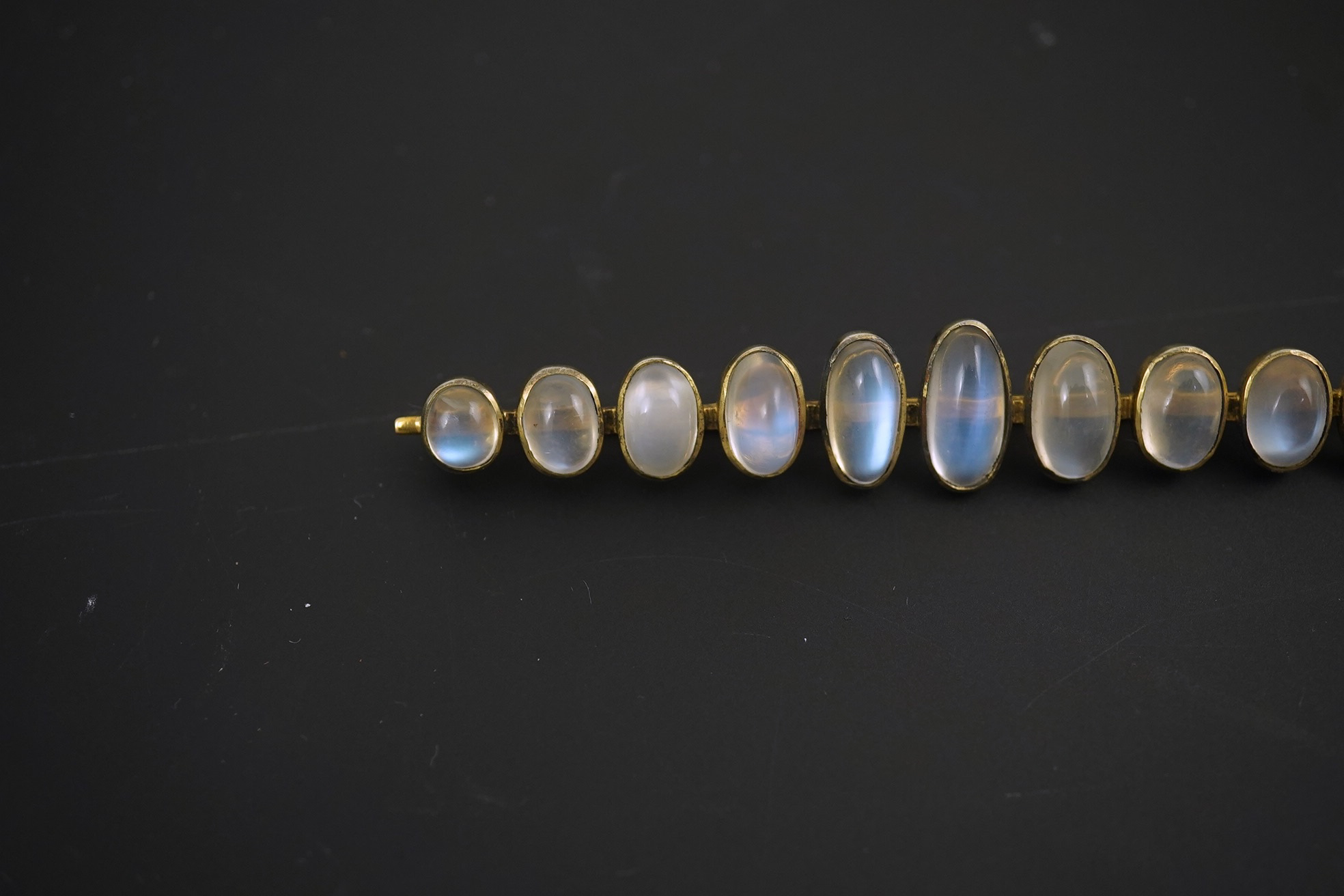 A gold and eleven stone graduated cabochon moonstone set bar brooch